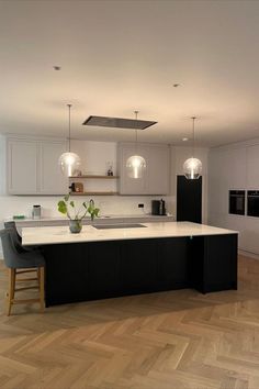 a large kitchen with an island in the middle and two lights hanging from the ceiling