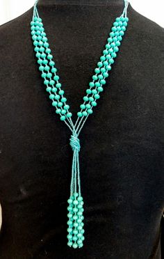 a woman wearing a necklace with turquoise beads and tassels on the front of her neck