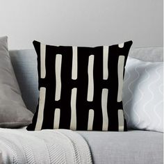 a black and white pillow sitting on top of a couch next to a gray wall