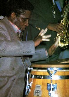 a man is playing the saxophone in front of a drum and some other people behind him