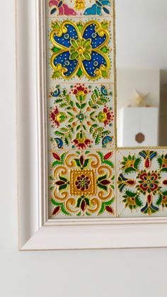 a white frame with colorful tiles on it and a mirror in the corner behind it