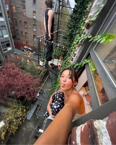 a woman standing on top of a balcony next to a man walking down the street