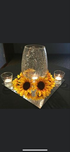 two sunflowers are placed in front of a wine glass on a black table