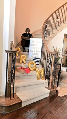 a man sitting on top of a set of stairs next to a stair case with gold letters