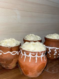 three clay pots with white icing sitting on a table