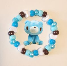 a small blue teddy bear with brown and white beads on it's bracelets