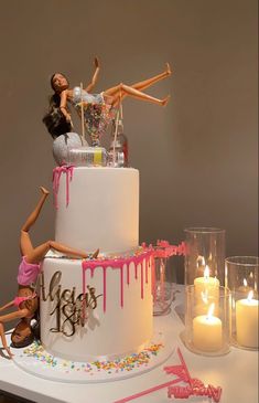 there is a cake decorated with barbie dolls on top and candles in the bottom tier