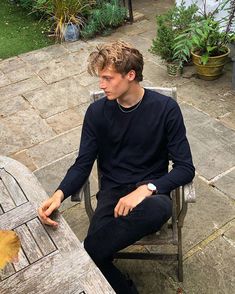 a young man sitting at a table outside