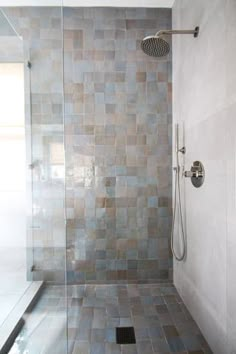 a walk in shower sitting next to a glass door and tiled wall with an open shower head