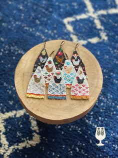 the beaded earrings are sitting on top of a small wooden stand in front of a blue rug