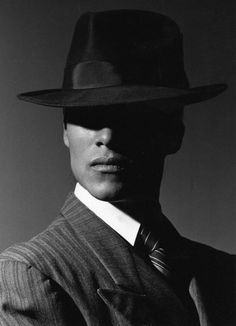 a black and white photo of a man in a suit with a hat on his head