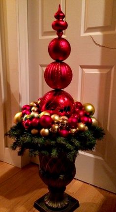 a vase filled with christmas ornaments on top of a wooden floor next to a door