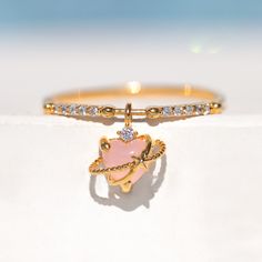 Fall in love with the beauty of our Aphrodite Ring! This petite pink ring features a cubic heart-shaped stone and puts a fun twist on the celestial motif. Pink Open Ring Crystal Promise Ring, Dainty Pink Crystal Ring, Pink Open Ring Jewelry For Proposal, Dainty Pink Crystal Promise Ring, Pink Heart Ring For Promise, Pink Open Ring For Proposal, Pink Gemstone Heart Ring, Pink Heart-shaped Jewelry For Proposal, Dainty Pink Open Heart Ring