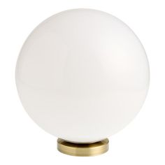 a white ball light sitting on top of a wooden stand with a gold metal base