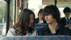 two people sitting on a bus looking at each other