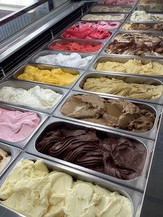 an assortment of ice creams in trays on display