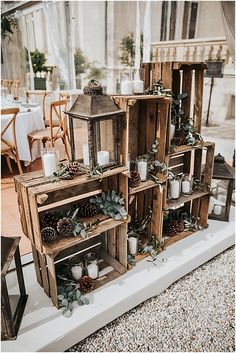 wooden crates filled with candles and greenery on top of a white tablecloth covered floor