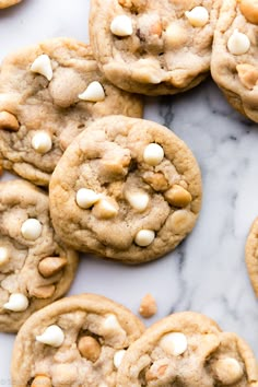 cookies with white chocolate chips and nuts on a marble counter top, ready to be eaten