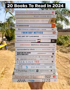 a stack of books sitting on top of each other in front of a dirt field