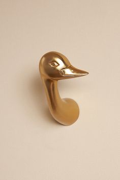 a gold colored duck shaped object on a white surface with one eye open and the other half closed