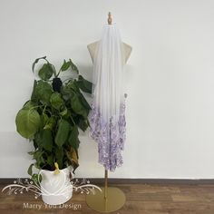 a mannequin next to a potted plant on a wooden floor in front of a white wall