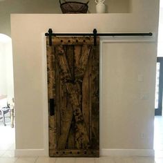 a large wooden door sitting in the middle of a room next to a white wall