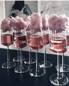 four wine glasses filled with pink cotton candy on top of a black table next to each other