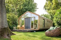 a small wooden cabin sitting in the middle of a lush green field next to a tree