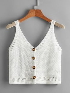 a white crop top with buttons on the front and back, hanging from a wooden hanger