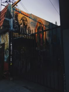 a large mural on the side of a building behind a fence with a light pole