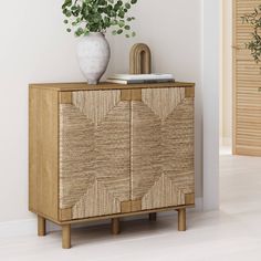 a white vase sitting on top of a wooden cabinet next to a plant in a pot