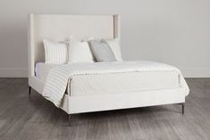 a white bed sitting on top of a wooden floor