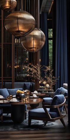 a living room filled with blue couches and round tables surrounded by hanging lights above them