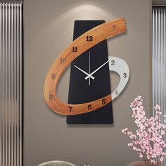 a clock that is on the wall next to a vase with pink flowers in it