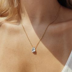 a woman wearing a gold necklace with a heart shaped diamond on the front and side