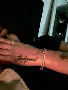 a person with a tattoo on their arm and the word godgaed written in cursive writing