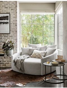 a living room filled with furniture and a fire place in front of a brick wall