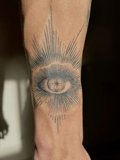 a person's leg with an eye tattoo on it and sunbursts