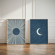 two framed art prints on the floor in an empty room with wood floors and white walls