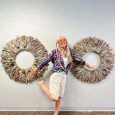 a woman standing in front of two wreaths made out of toothpick sticks