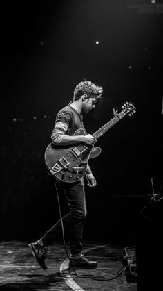 a man standing on stage with a guitar