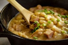 a wooden spoon in a black pot filled with food