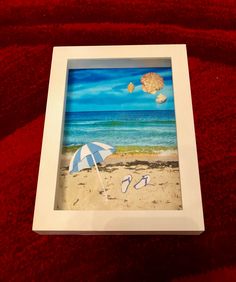 an image of a beach scene with umbrella and flip flops in the sand on a red blanket