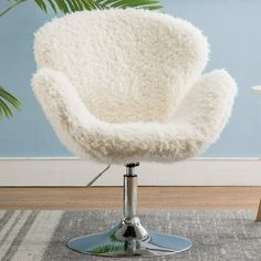 a white chair sitting on top of a wooden floor next to a potted plant