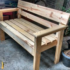 a wooden bench sitting next to a potted plant on top of a cement floor