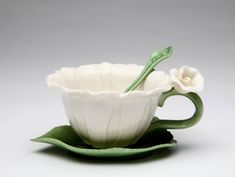 a white flower sitting on top of a green saucer with a spoon in it