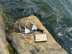 a book and headphones are sitting on a rock near the water's edge