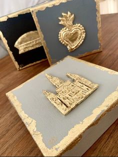 two gold and silver brooches sitting on top of a wooden table next to each other