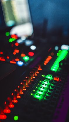 a close up of a computer keyboard with many lights on the keys and a monitor in the background