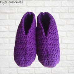 purple crocheted slippers hanging on a brick wall in front of a white brick wall